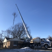 A crane is in the air next to a truck.