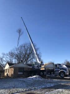 A crane is in the air next to a truck.