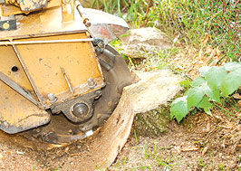 A yellow tractor is cutting through the ground.